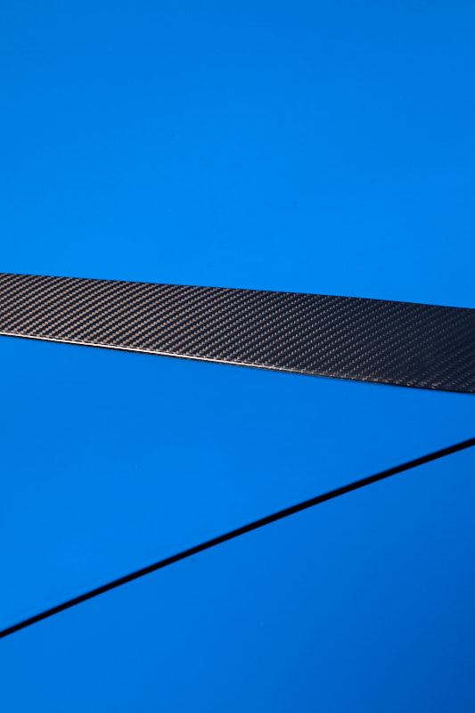 Carbon fibre blade crossing bright blue bodywork
