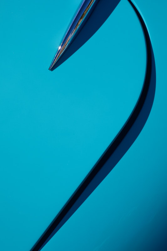 Chrome trim spear and its sweeping shadow across turquoise bodywork